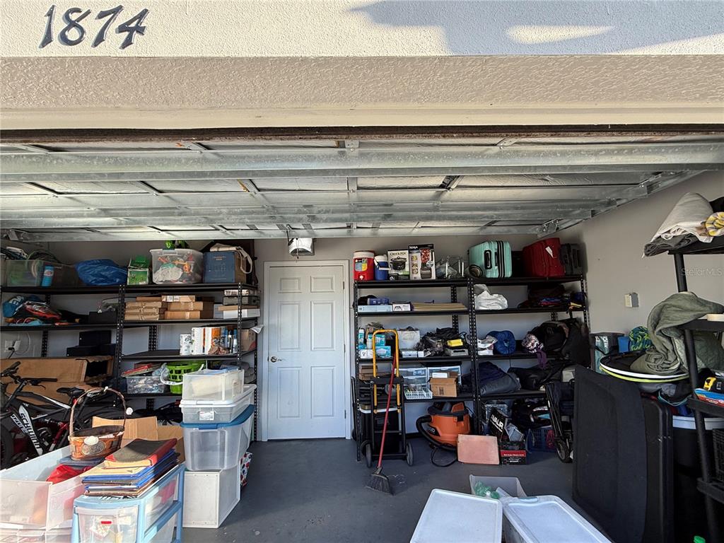 A garage interior features metal shelving units filled with storage bins and household items — 1874 HICKORY BLUFF ROAD, KISSIMMEE, FL