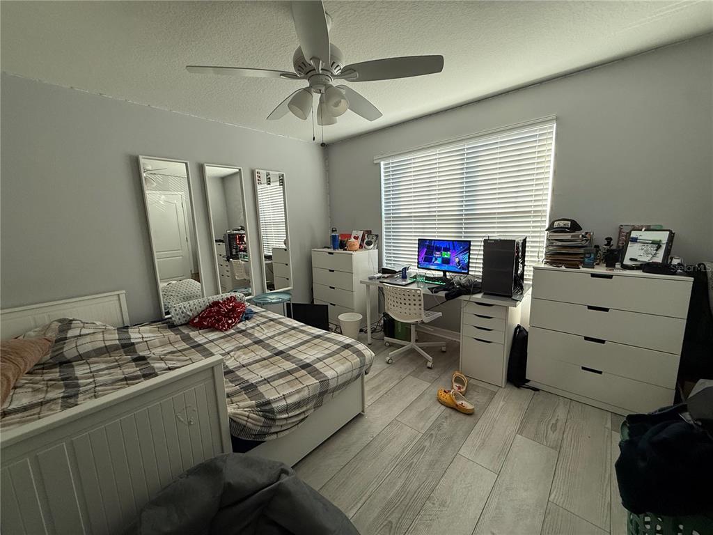 A bedroom features a bed, a desk with a computer, and white dressers on wood-look flooring — 1874 HICKORY BLUFF ROAD, KISSIMMEE, FL