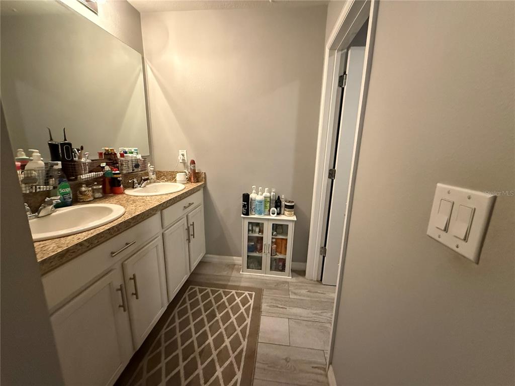 A bathroom features a double vanity with white cabinets, granite countertops, and a small storage unit — 1874 HICKORY BLUFF ROAD, KISSIMMEE, FL