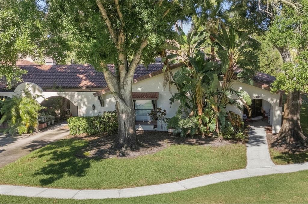 A single-story house with a tiled roof, arched entryway, and mature trees in the yard — 3446 TARPON WOODS BOULEVARD, PALM HARBOR, FL