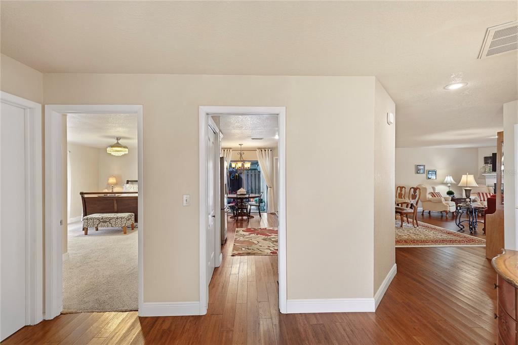A hallway with hardwood floors leads to a bedroom, a dining area, and a living room — 3446 TARPON WOODS BOULEVARD, PALM HARBOR, FL