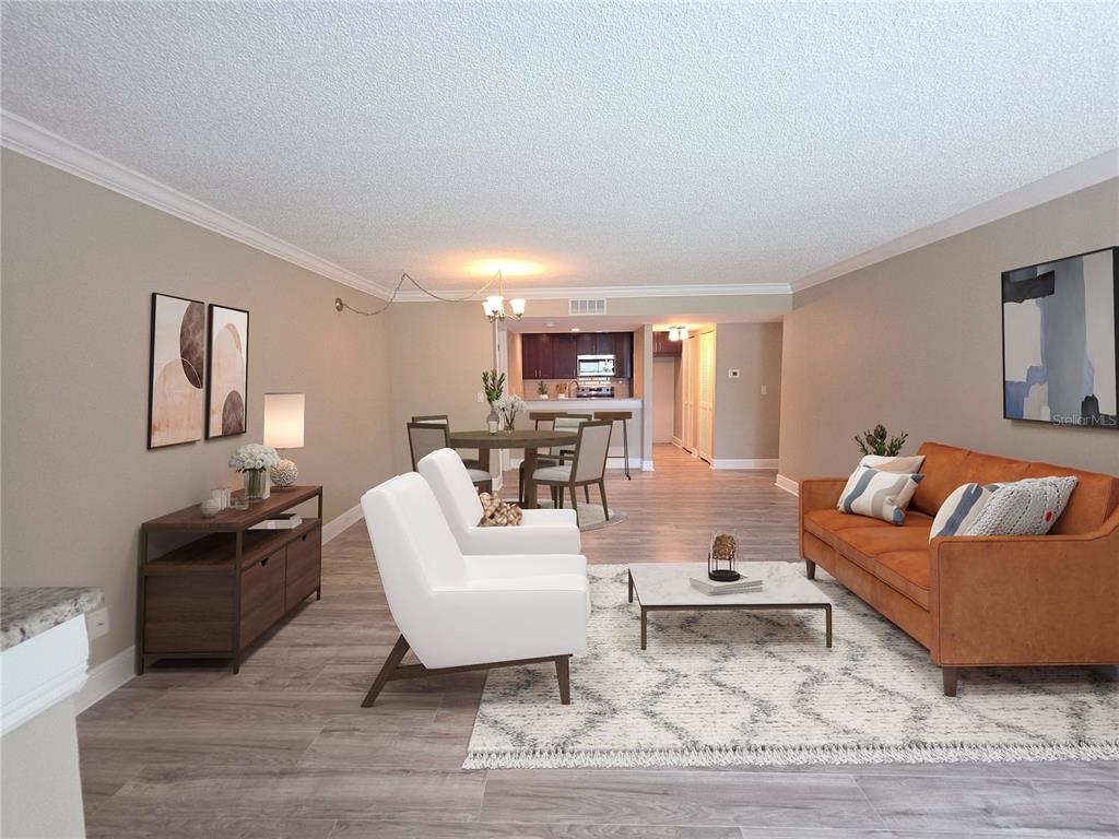 An open-concept living and dining area features wood-look flooring, white chairs, and a leather sofa — 2599 COUNTRYSIDE BOULEVARD UNIT 117, CLEARWATER, FL