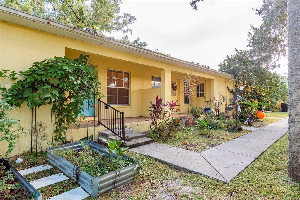 Exterior view of a yellow single-story building with a covered porch and a garden bed — 406 S BAYVIEW BOULEVARD UNIT 1, OLDSMAR, FL
