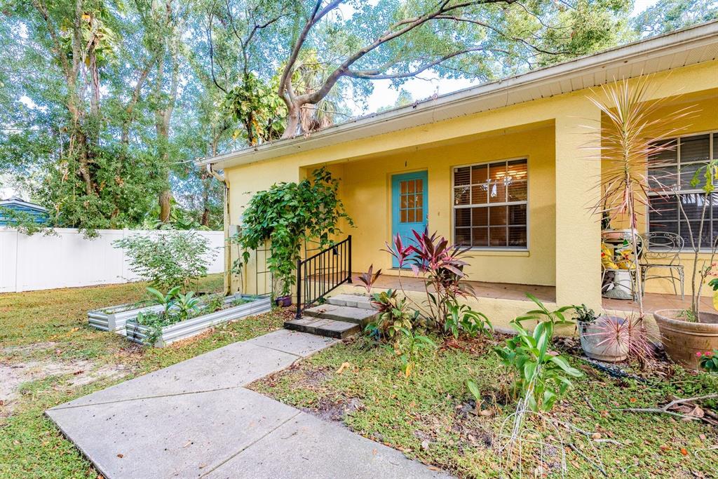 A yellow house with a blue front door, a covered porch, and a garden bed — 406 S BAYVIEW BOULEVARD UNIT 1, OLDSMAR, FL