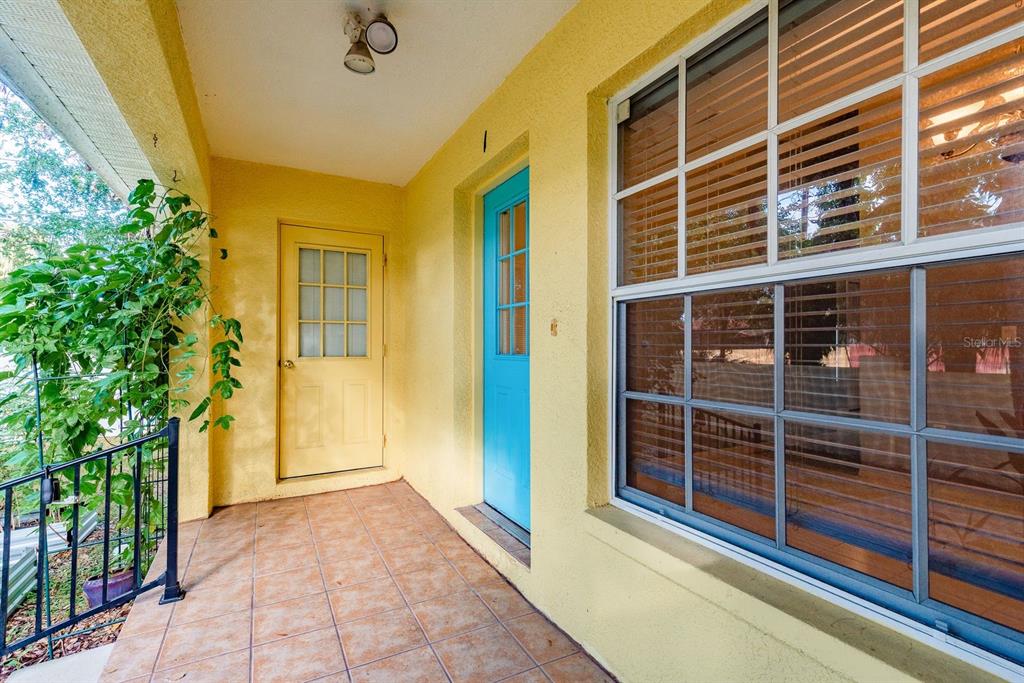 A yellow porch features a blue door, a yellow door, and a large grid window — 406 S BAYVIEW BOULEVARD UNIT 1, OLDSMAR, FL