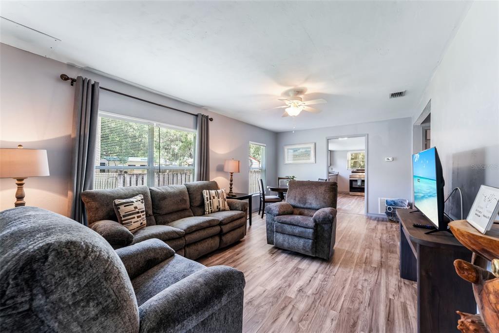 A living room features gray furniture, wood-look flooring, and a ceiling fan — 302 PARK AVENUE, HASTINGS, FL