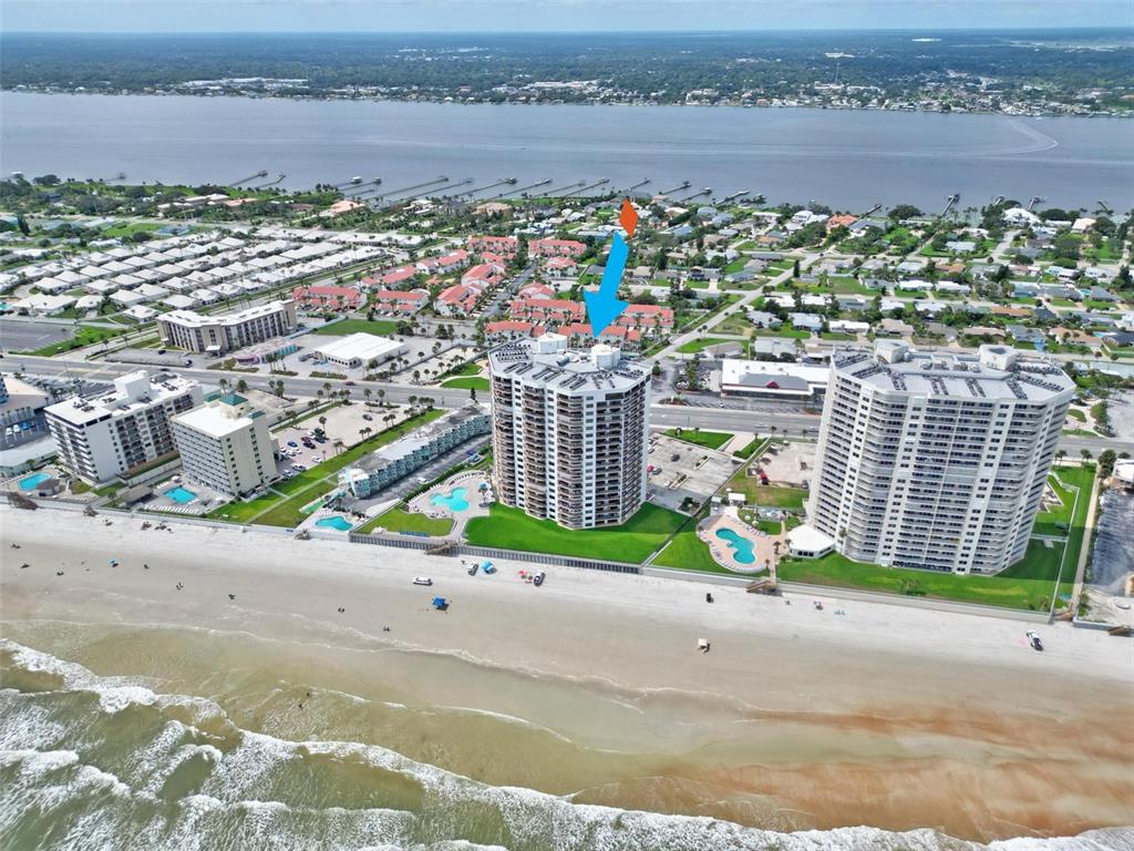 An aerial view shows high-rise beachfront condominiums with swimming pools along a sandy coastline — 2555 S ATLANTIC AVENUE UNIT 1704, DAYTONA BEACH SHORES, FL
