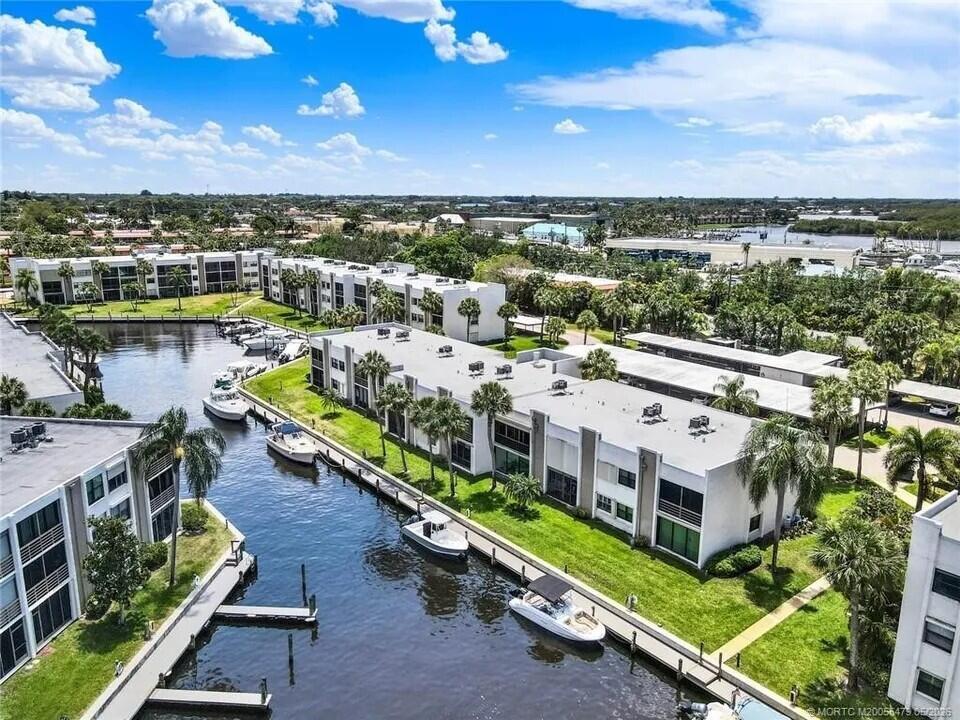 An aerial view of a waterfront apartment complex with boat slips and docked motorboats — 1950 SW Palm City Road # 102, Stuart FL 34994, STUART, FL