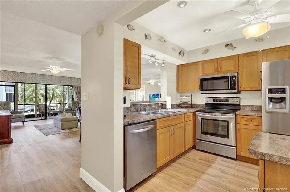 A kitchen with wood cabinets and stainless steel appliances opens to a living area — 1950 SW Palm City Road # 102, Stuart FL 34994, STUART, FL