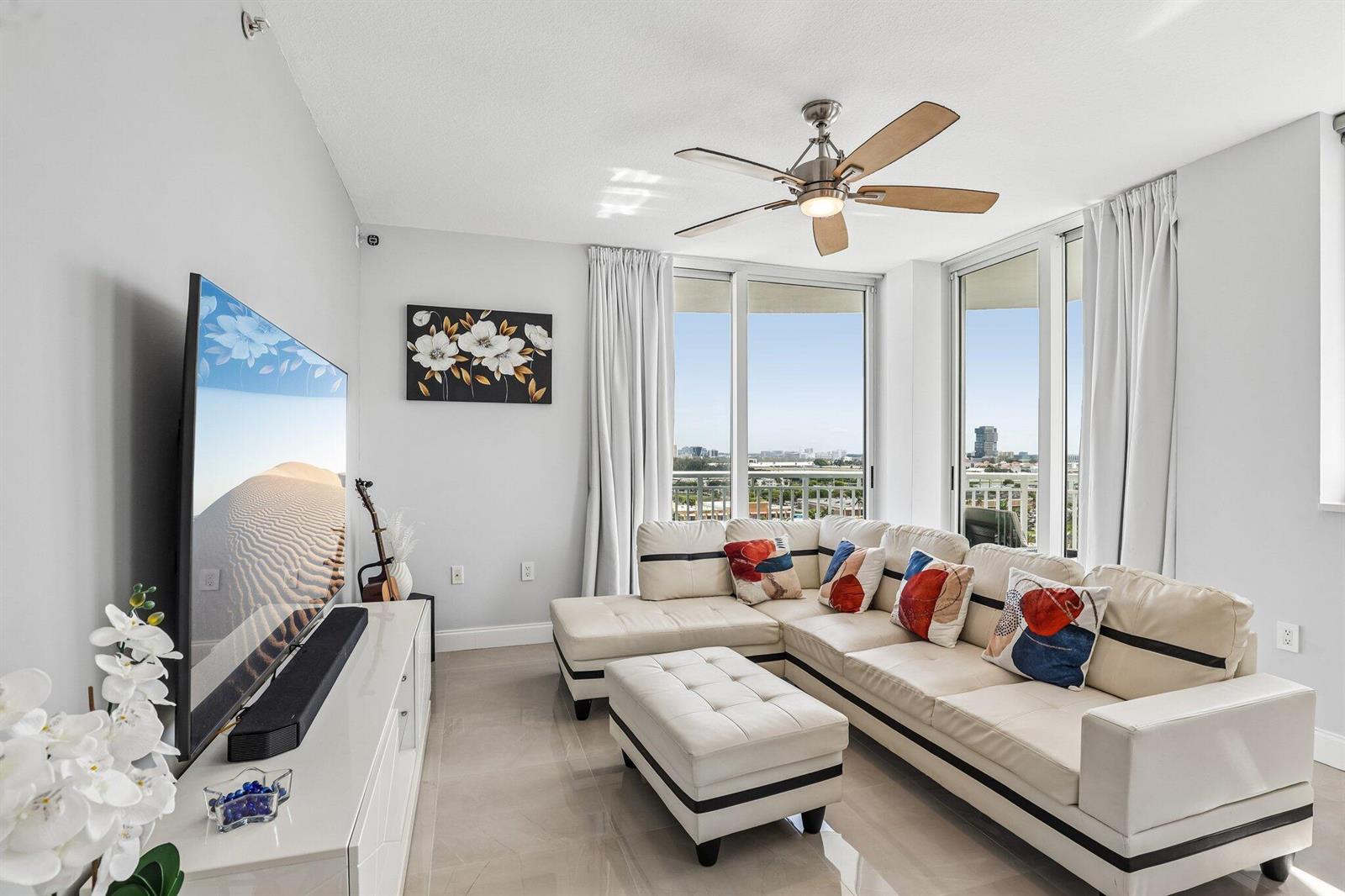 A living room features a white sectional sofa, a television, and floor-to-ceiling windows with views — 1755 E Hallandale Beach Boulevard, Hallandale Beach FL 33009, HALLANDALE BEACH, FL