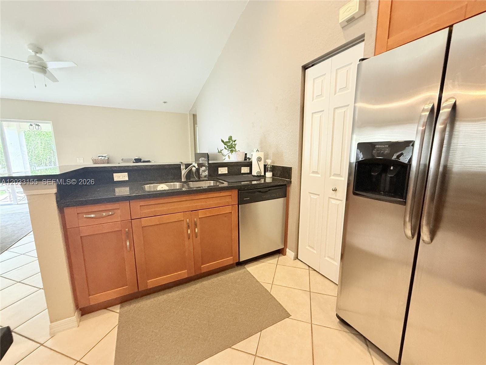 A kitchen features wood cabinets, black countertops, stainless steel appliances, and a tiled floor — 1530 Canary Island Dr, Weston FL 33327, WESTON, FL