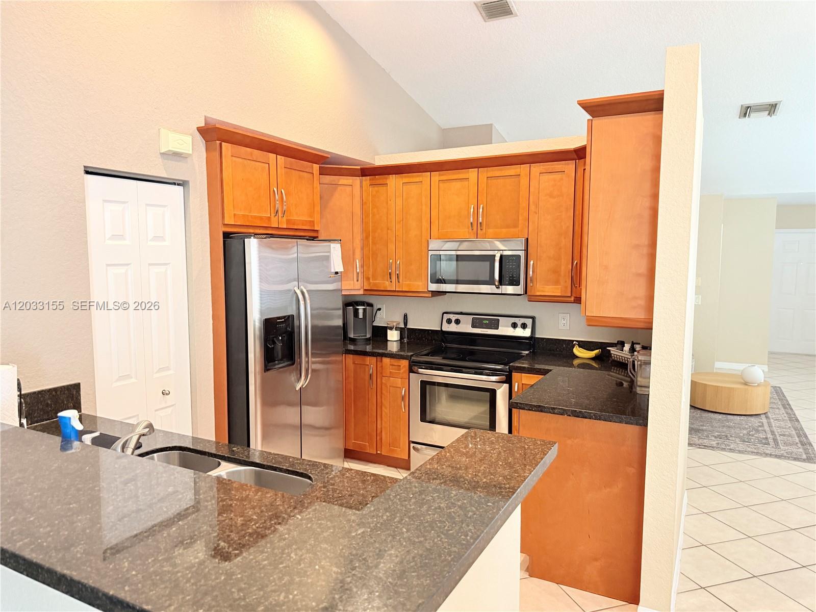 A kitchen features wood cabinets, stainless steel appliances, and dark granite countertops — 1530 Canary Island Dr, Weston FL 33327, WESTON, FL