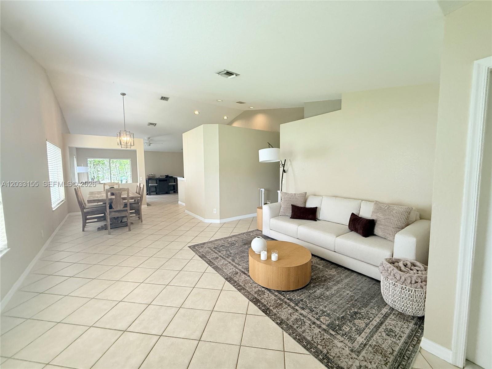 A living room with tile floors, a white sofa, and an adjacent dining area — 1530 Canary Island Dr, Weston FL 33327, WESTON, FL