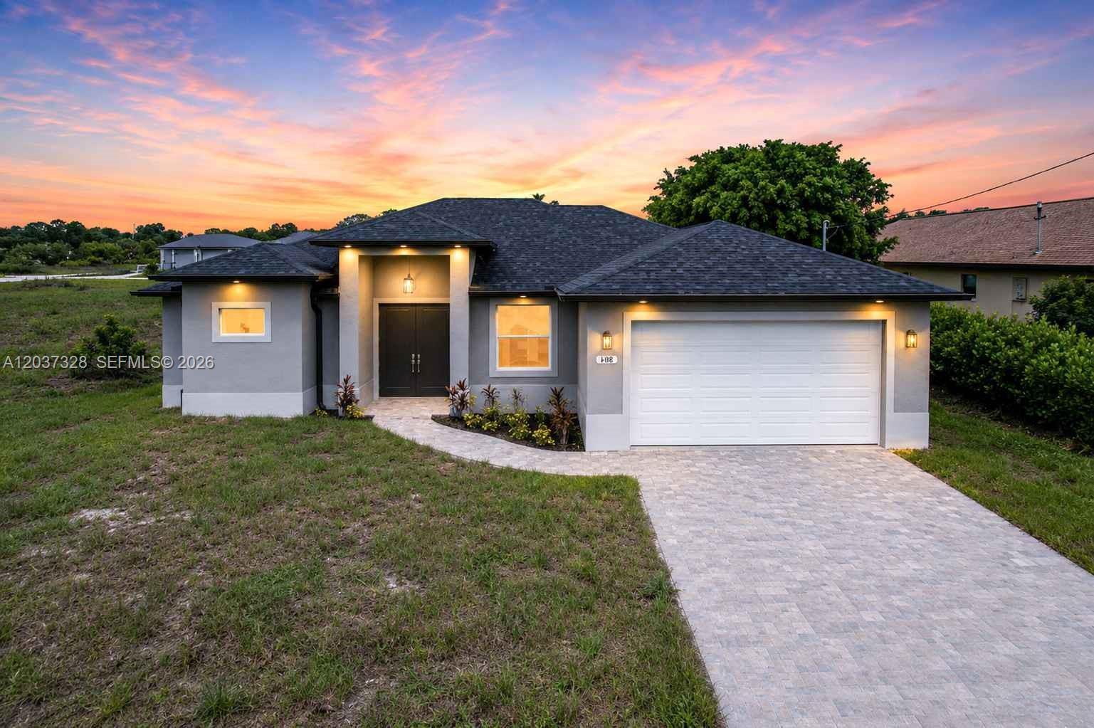 A single-story house with a gray stucco exterior, dark roof, and a paved driveway — 3909 16TH ST W, Lehigh Acres FL 33971, LEHIGH ACRES, FL