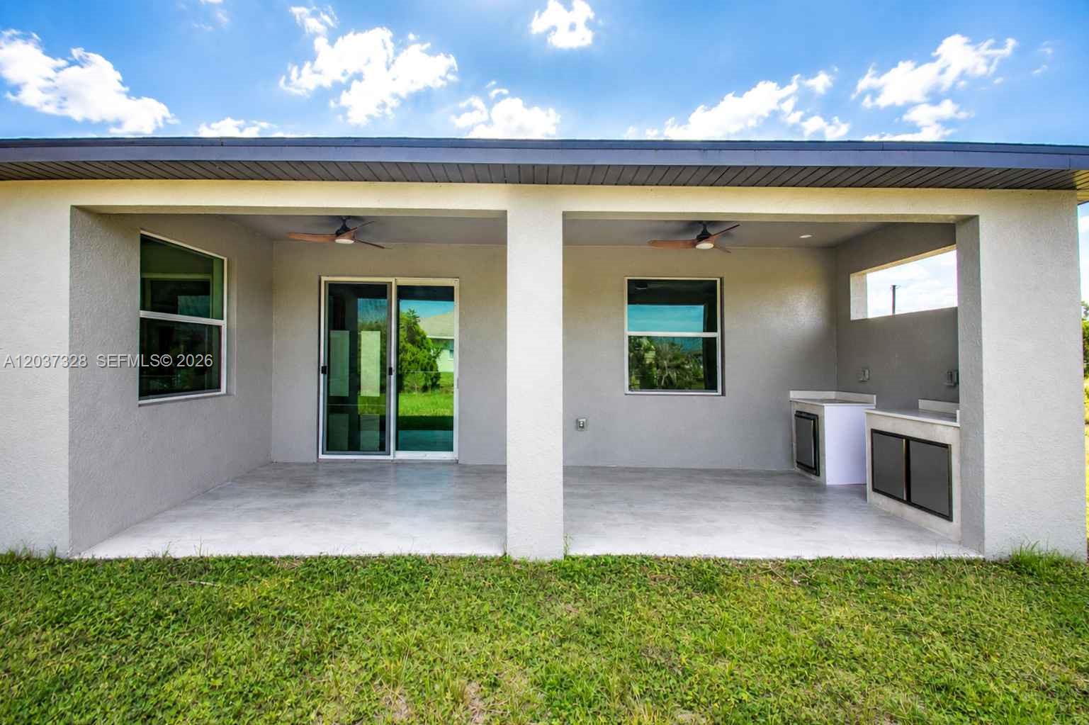 A covered patio features a concrete floor, two ceiling fans, and an outdoor kitchen area — 3909 16TH ST W, Lehigh Acres FL 33971, LEHIGH ACRES, FL