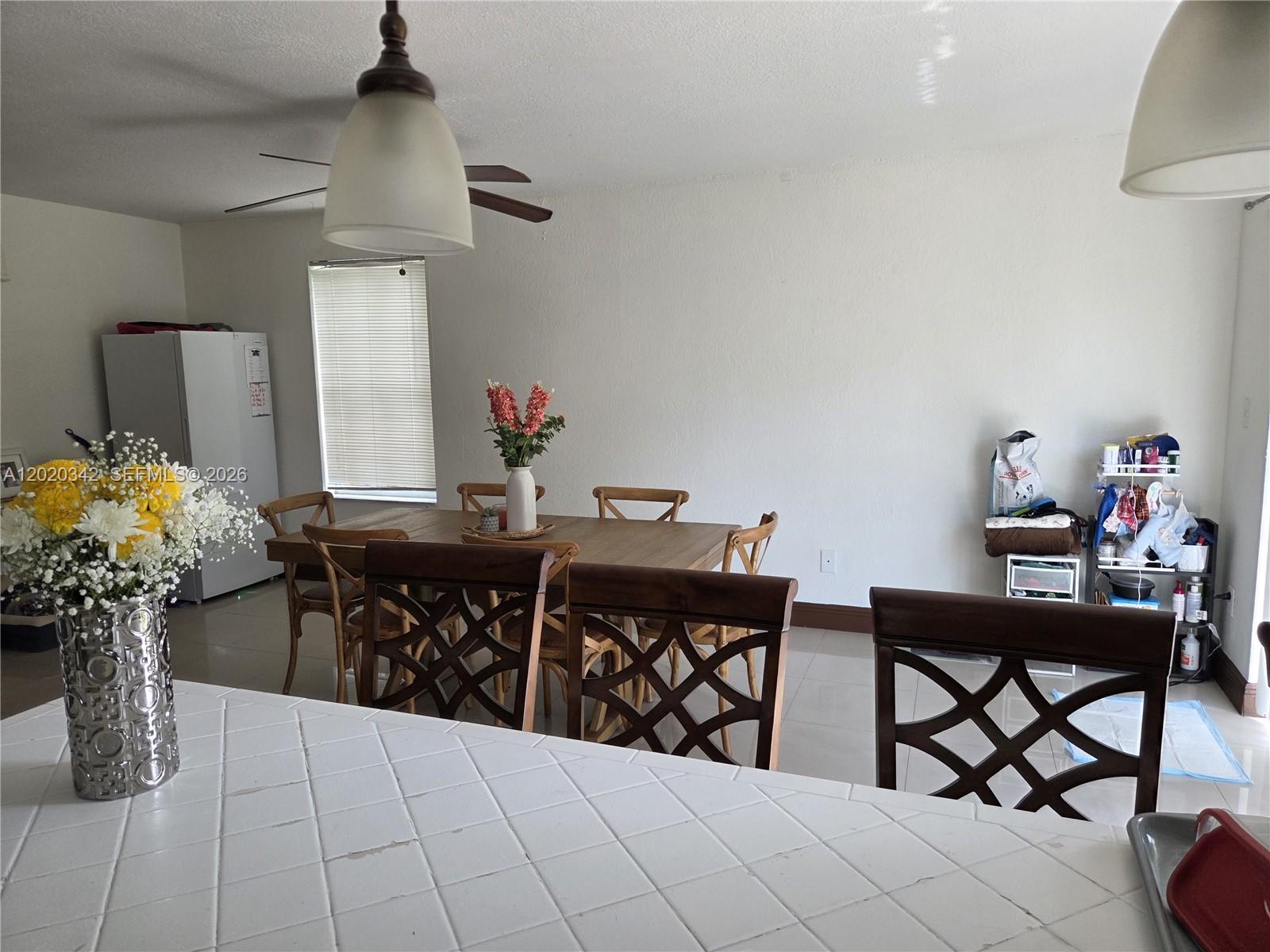 A patio with a dining set sits beside a house with a grassy backyard — 10120 SW 127th Ave, Miami FL 33186, MIAMI, FL