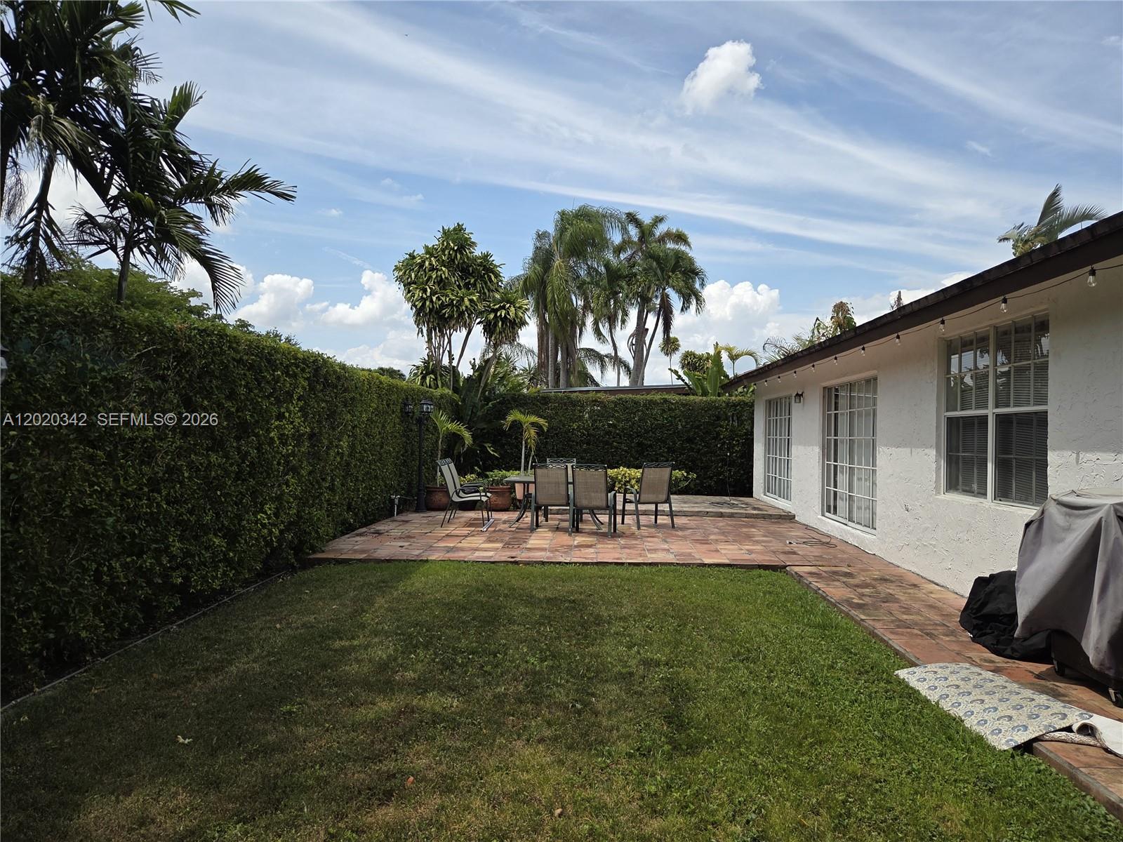 An empty living room features light-colored tile flooring, white walls, and sliding glass patio doors — 10120 SW 127th Ave, Miami FL 33186, MIAMI, FL