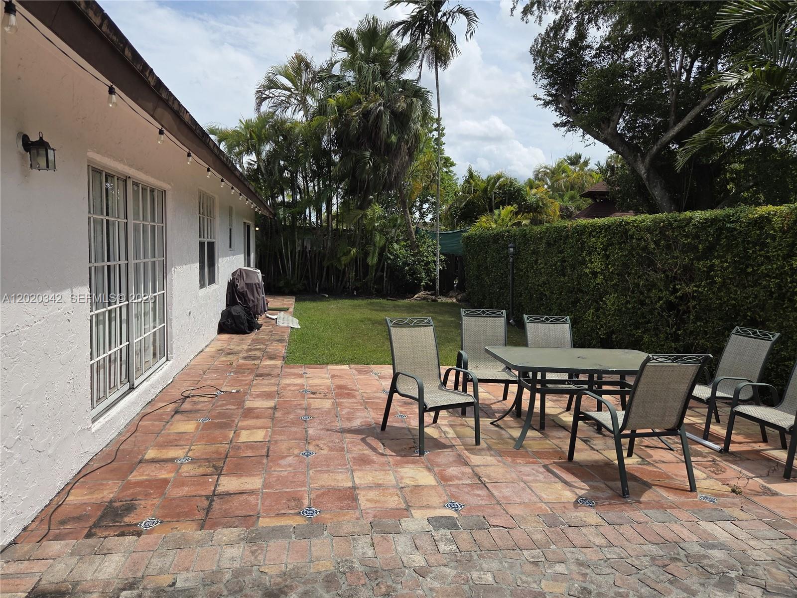 An empty living room features light-colored tile flooring, white walls, and sliding glass patio doors — 10120 SW 127th Ave, Miami FL 33186, MIAMI, FL