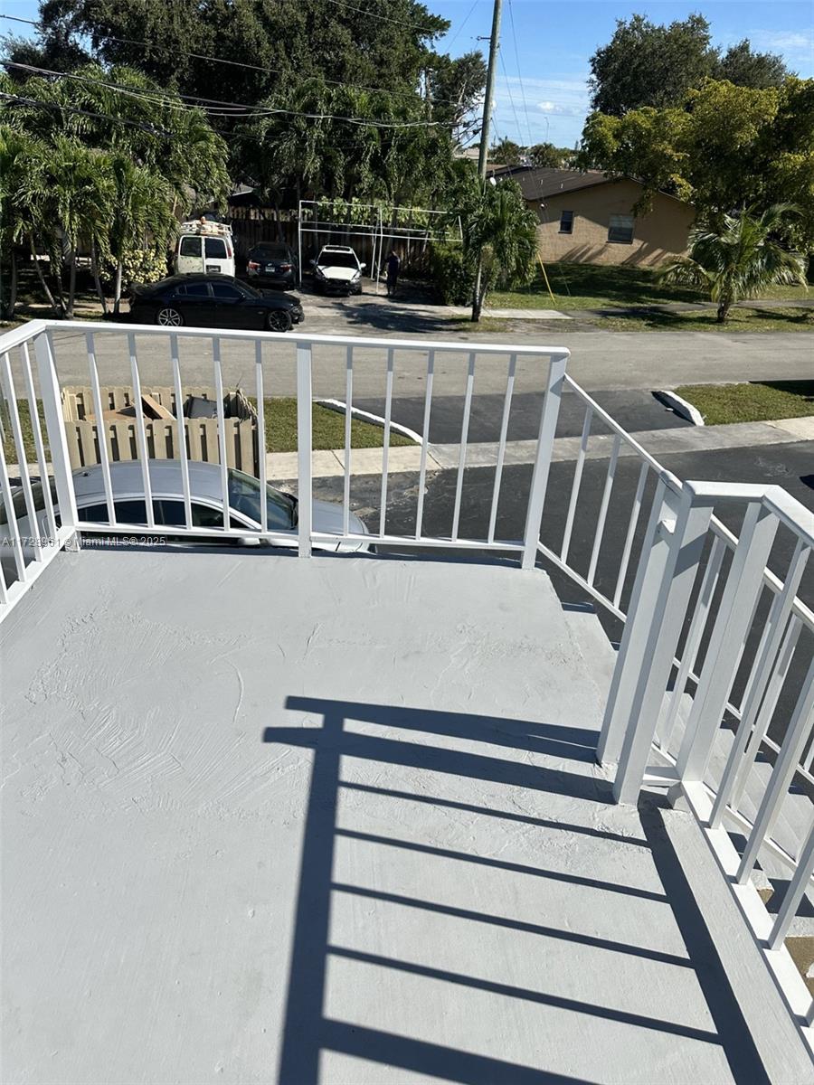 A view from an elevated balcony overlooking a parking area with several parked cars — 6101 Garfield St, Hollywood FL 33024, HOLLYWOOD, FL
