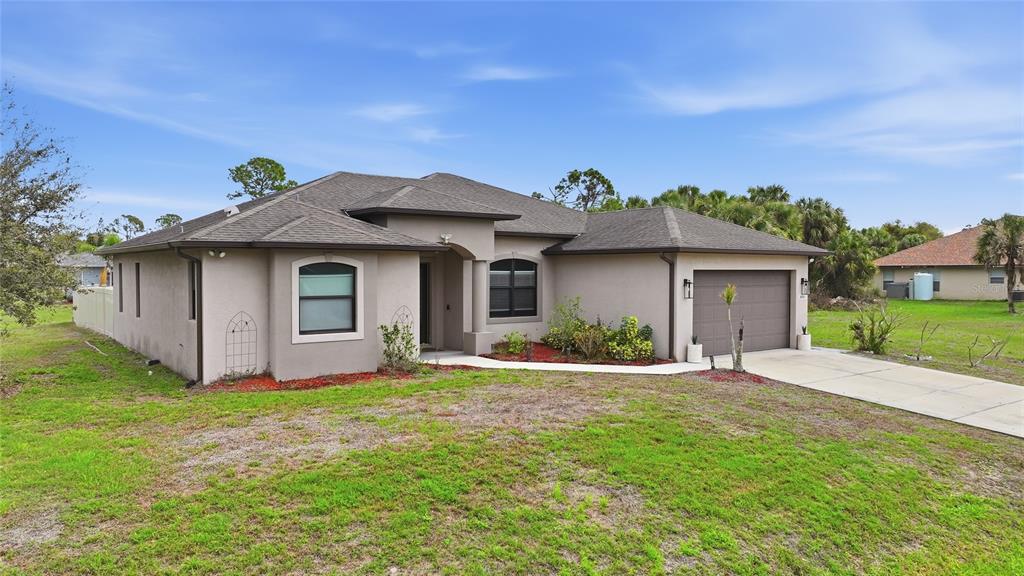 A single-story beige stucco house with a dark shingled roof and an attached garage — 1480 WISE DRIVE, NORTH PORT, FL