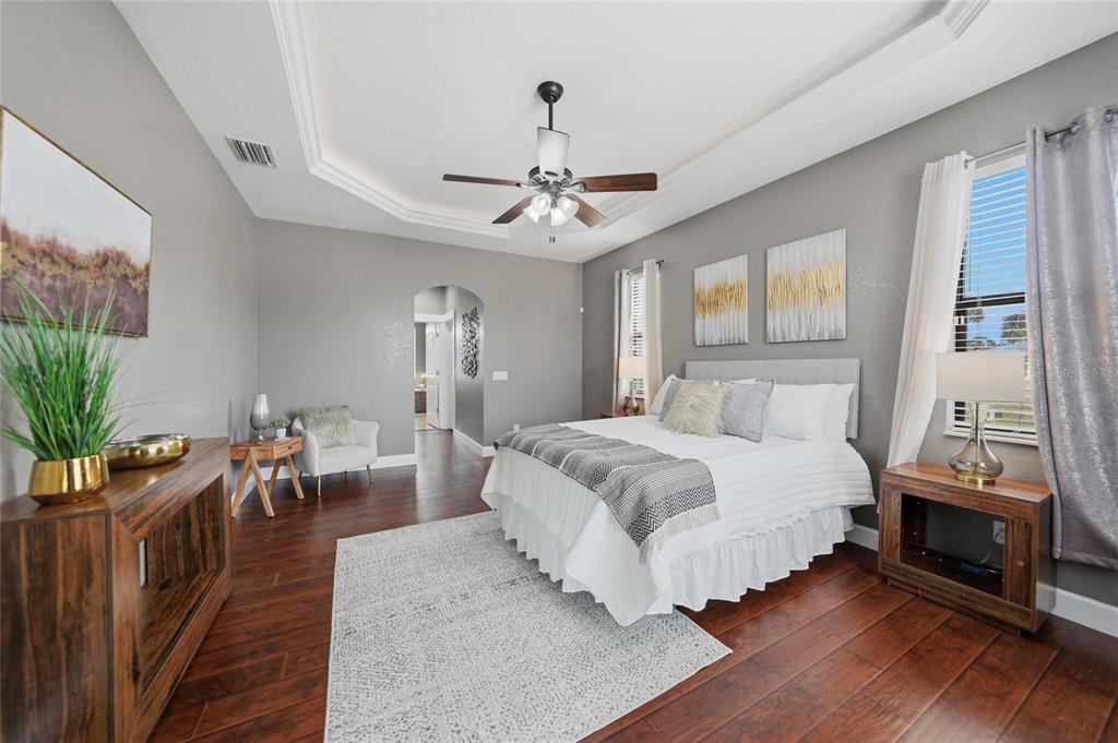 A bedroom features a tray ceiling, wood flooring, a ceiling fan, and a king-sized bed — 1480 WISE DRIVE, NORTH PORT, FL