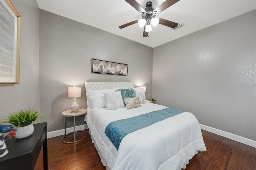 A bedroom features a bed with white bedding, a teal runner, and a ceiling fan — 1480 WISE DRIVE, NORTH PORT, FL