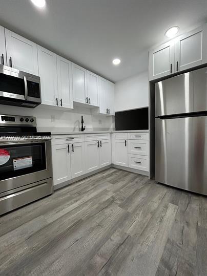 A kitchen features white cabinets, stainless steel appliances, and wood-look flooring — 8875 Fontainebleau Blvd # 201, Miami FL 33172, MIAMI, FL
