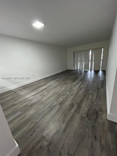 An empty room features wood-look flooring, white walls, a ceiling light, and vertical window blinds — 8875 Fontainebleau Blvd # 201, Miami FL 33172, MIAMI, FL
