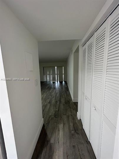 A hallway with wood-look flooring leads to a living area with sliding glass doors — 8875 Fontainebleau Blvd # 201, Miami FL 33172, MIAMI, FL