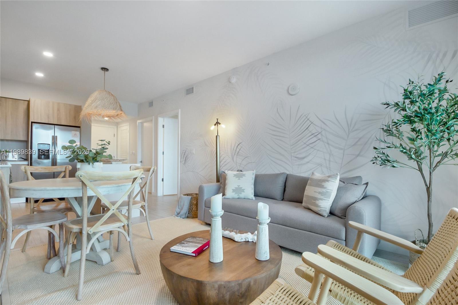 A living room and dining area feature a grey sofa, wooden table, and palm-patterned wallpaper — 3900 Biscayne Blvd # 911, Miami FL 33137, MIAMI, FL