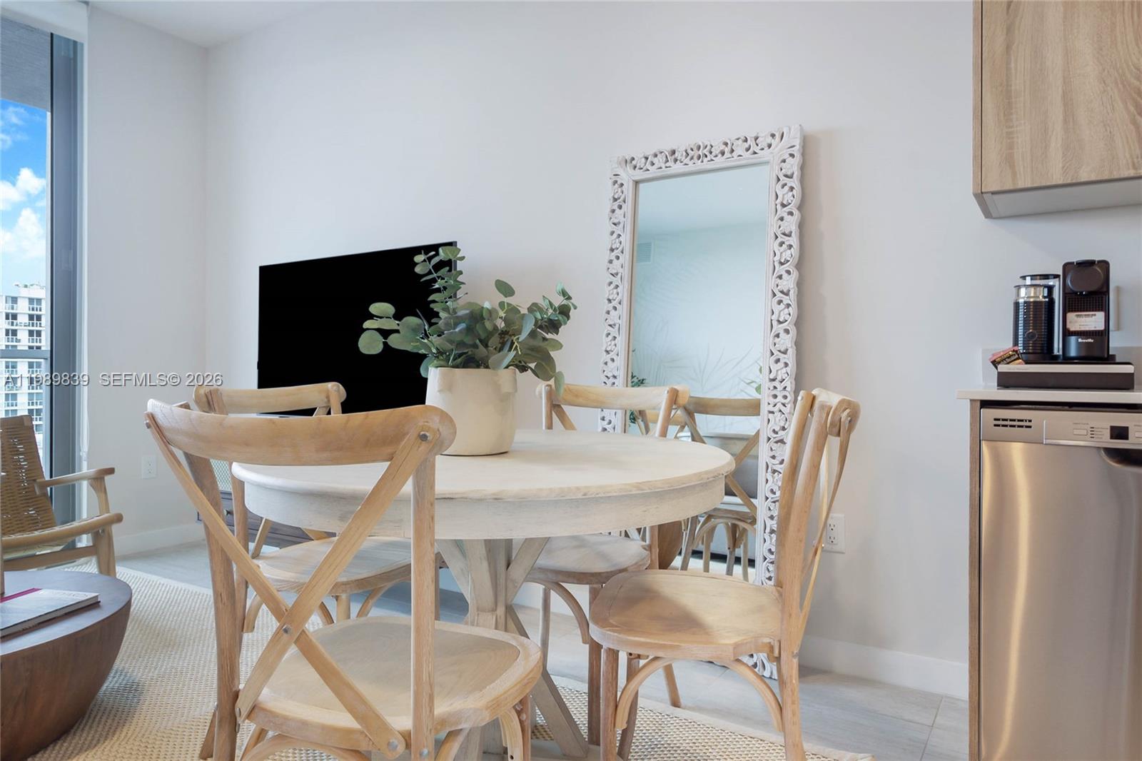 A dining area features a round wooden table, four cross-back chairs, and a floor mirror — 3900 Biscayne Blvd # 911, Miami FL 33137, MIAMI, FL