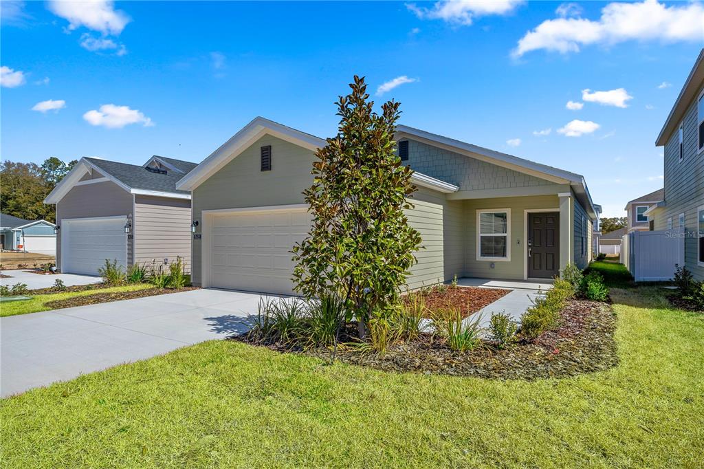 A single-story house with light green siding, a two-car garage, and a landscaped front yard — 8704 SW 67TH CIRCLE, OCALA, FL