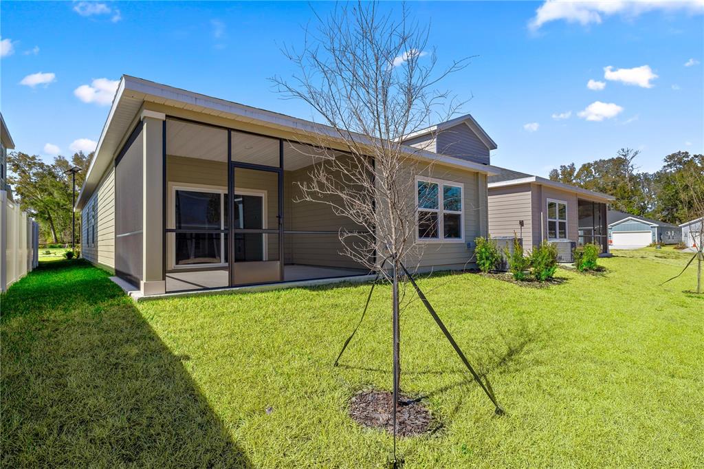 The exterior of a house features a screened-in patio and a grassy backyard — 8704 SW 67TH CIRCLE, OCALA, FL