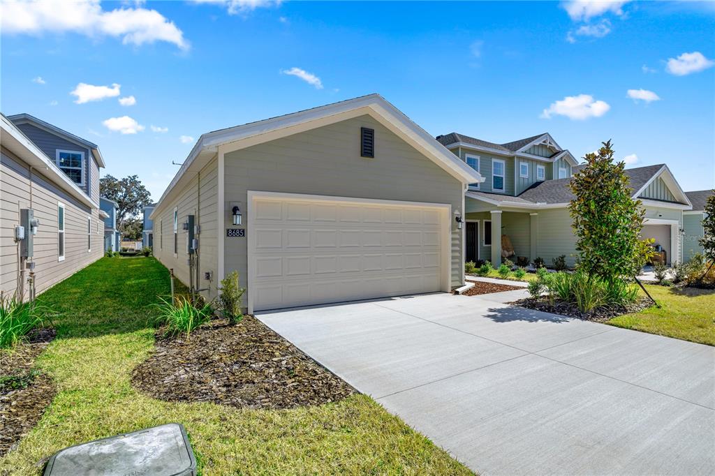 A light green single-story house with a two-car garage and a concrete driveway — 8704 SW 67TH CIRCLE, OCALA, FL
