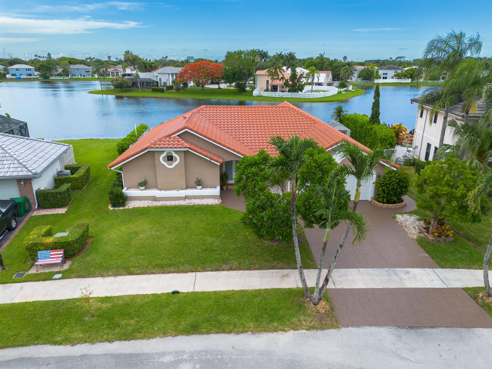 An aerial view shows a tan house with a red tile roof beside a lake — 14211 Appalachian Trail, Davie FL 33325, DAVIE, FL