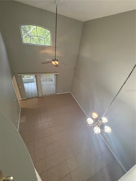 A high-ceilinged living room features tile flooring, a ceiling fan, and a hanging chandelier — 14864 LAGUNA BEACH CIRCLE, ORLANDO, FL