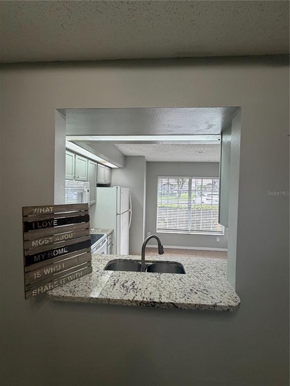 A kitchen pass-through window features a granite countertop, a stainless steel sink, and faucet — 14864 LAGUNA BEACH CIRCLE, ORLANDO, FL