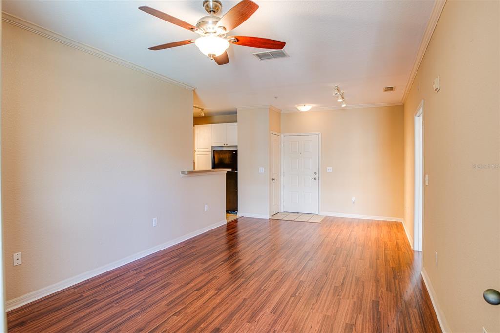 An open living area features wood-look flooring, a ceiling fan, and an adjacent kitchen — 4221 W SPRUCE STREET UNIT 1310, TAMPA, FL