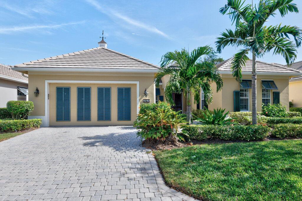 A single-story house with a beige stucco exterior, a tiled roof, and a paved driveway — 9190 Spring Time Drive, Vero Beach FL 32963, VERO BEACH, FL