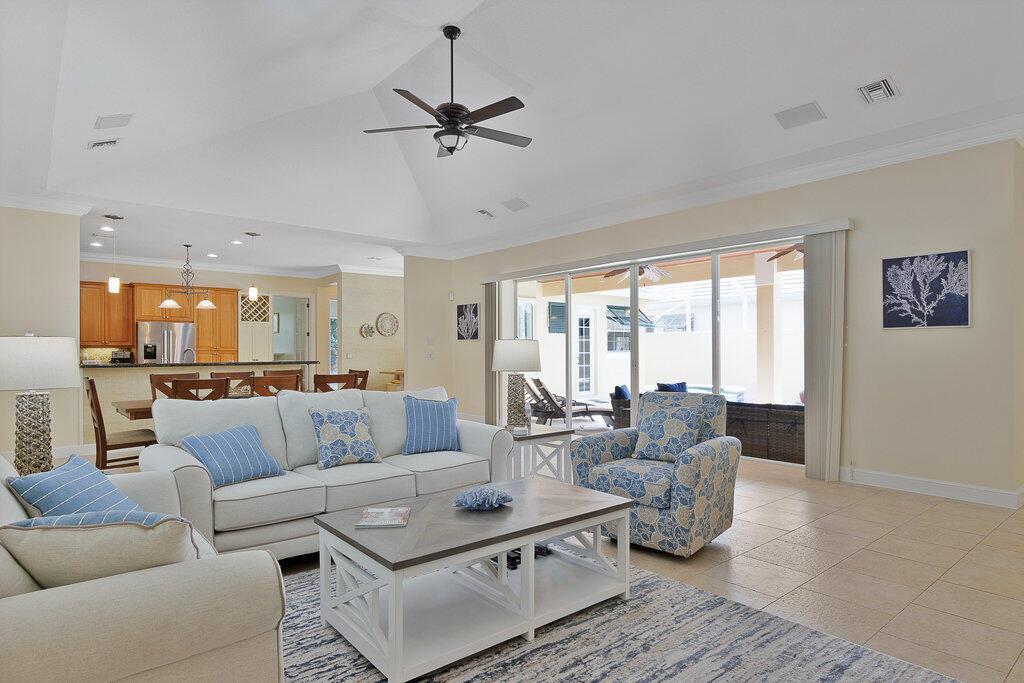 A living room with a vaulted ceiling, tile floors, and sliding doors opening to a patio — 9190 Spring Time Drive, Vero Beach FL 32963, VERO BEACH, FL
