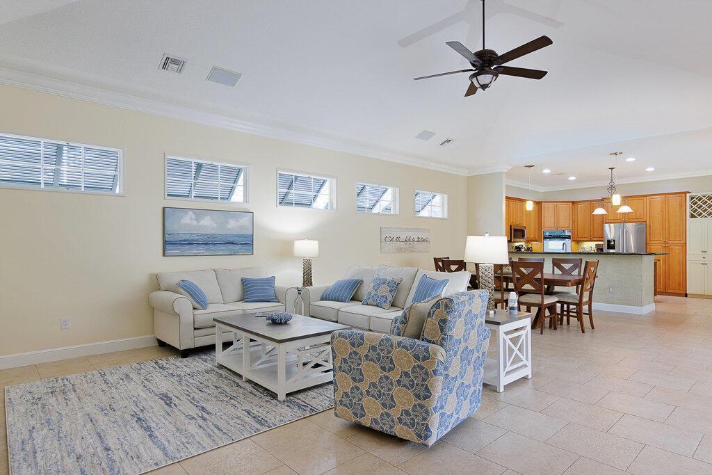 A living room with light tile floors, a vaulted ceiling, and an open kitchen area — 9190 Spring Time Drive, Vero Beach FL 32963, VERO BEACH, FL