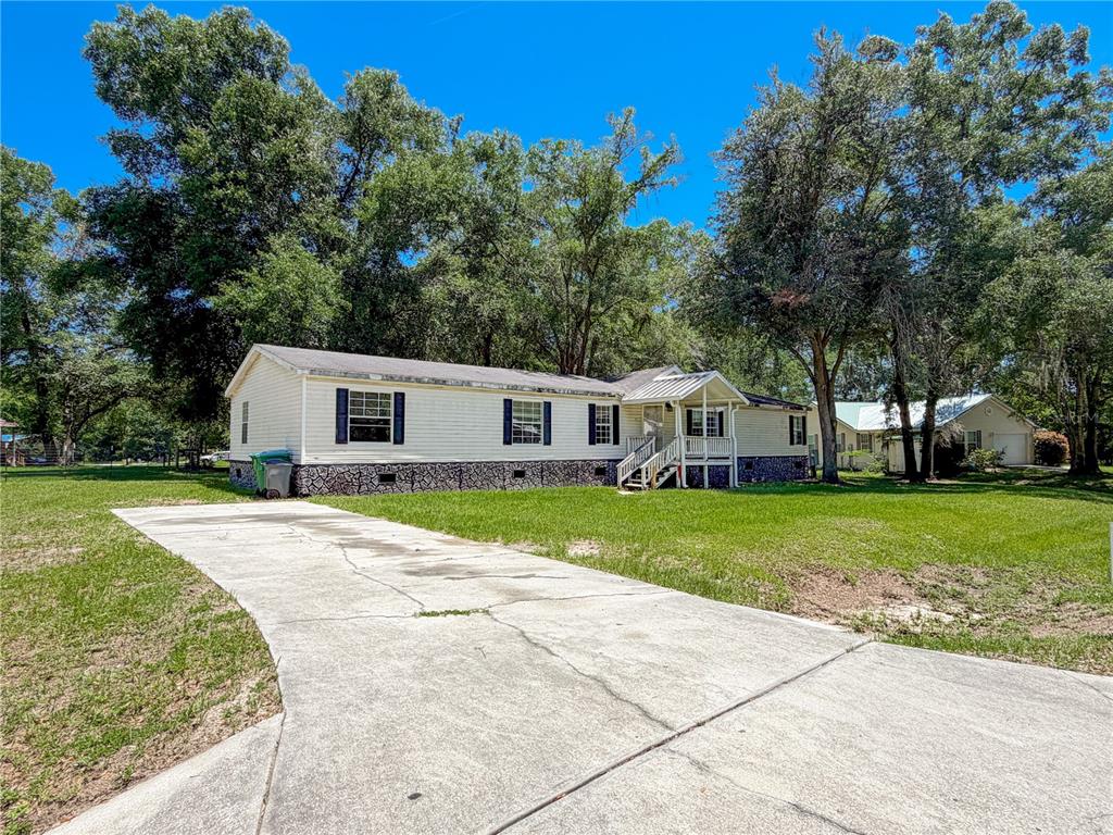 A single-story manufactured home with a concrete driveway and a covered front porch — 303 NW KENSINGTON LANE, LAKE CITY, FL
