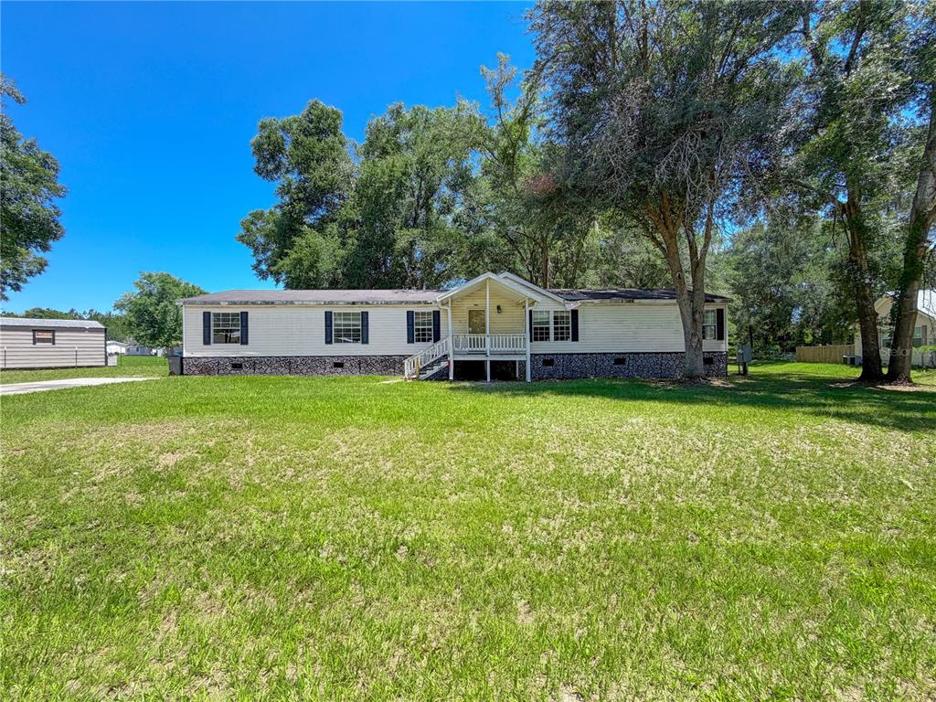 A single-story manufactured home with white siding and a front porch sits on a lawn — 303 NW KENSINGTON LANE, LAKE CITY, FL