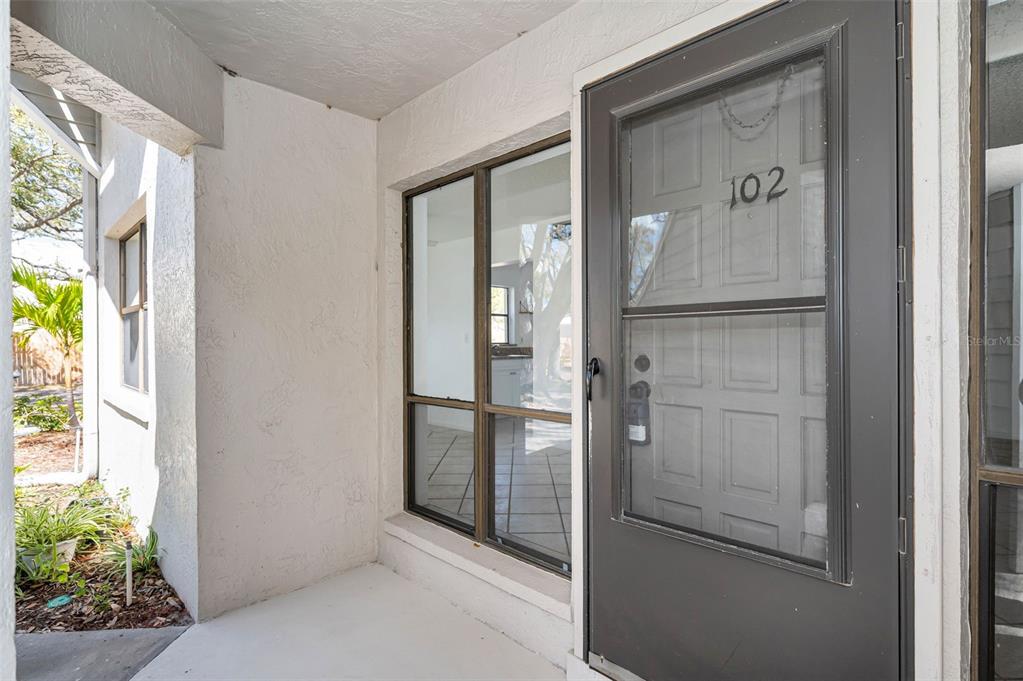 A covered entryway features a gray front door labeled 102 next to a large window — 10626 LONGWOOD DRIVE UNIT 102, SEMINOLE, FL
