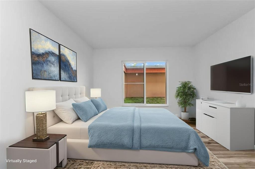 A bedroom features a bed with blue bedding, a white dresser, and a window view — 2290 AARON STREET UNIT 109, PORT CHARLOTTE, FL