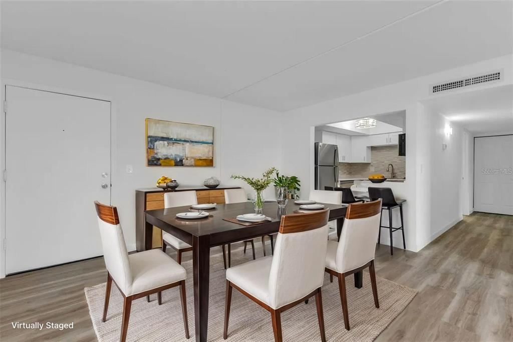 A dining area with a dark wood table, white chairs, and an adjacent kitchen pass-through — 2290 AARON STREET UNIT 109, PORT CHARLOTTE, FL