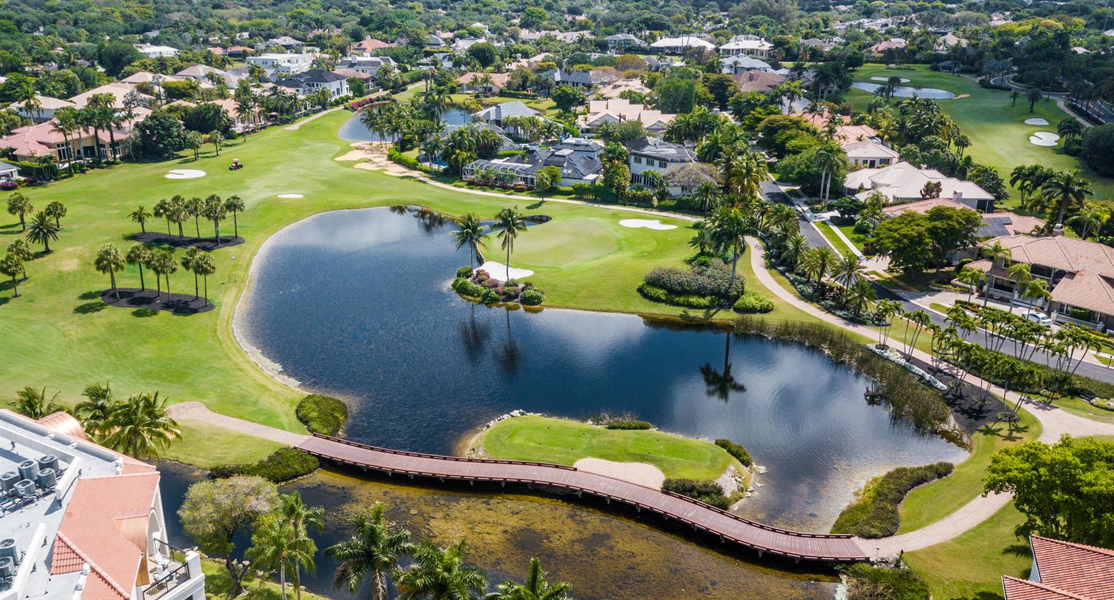 An aerial view shows a golf course with a large pond, a wooden bridge, and houses — 7369 Orangewood Lane # 303, Boca Raton FL 33433, BOCA RATON, FL