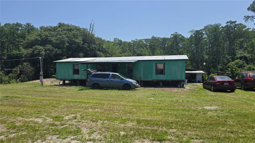 A green mobile home sits on a grassy lot with two cars parked in front — 135 STARLIGHT ROAD, CRESCENT CITY, FL