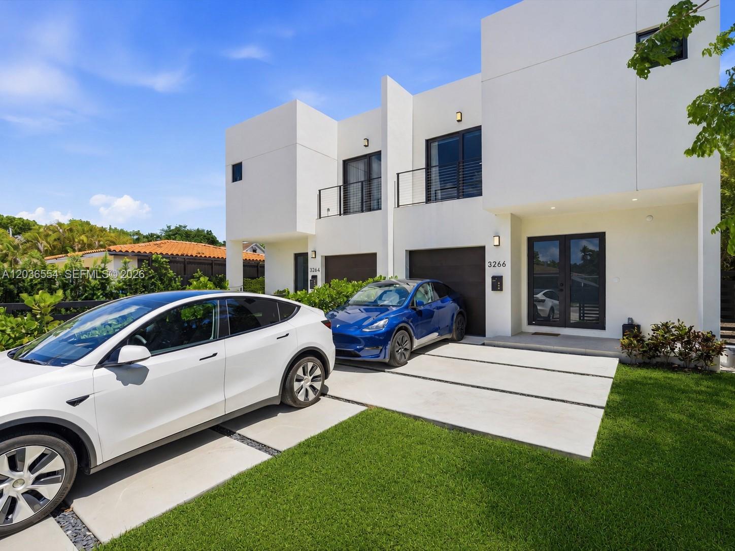 Two modern white townhouses with driveways and parked cars under a clear blue sky — 3266 SW 25th Ter # 3266, Miami FL 33133, MIAMI, FL