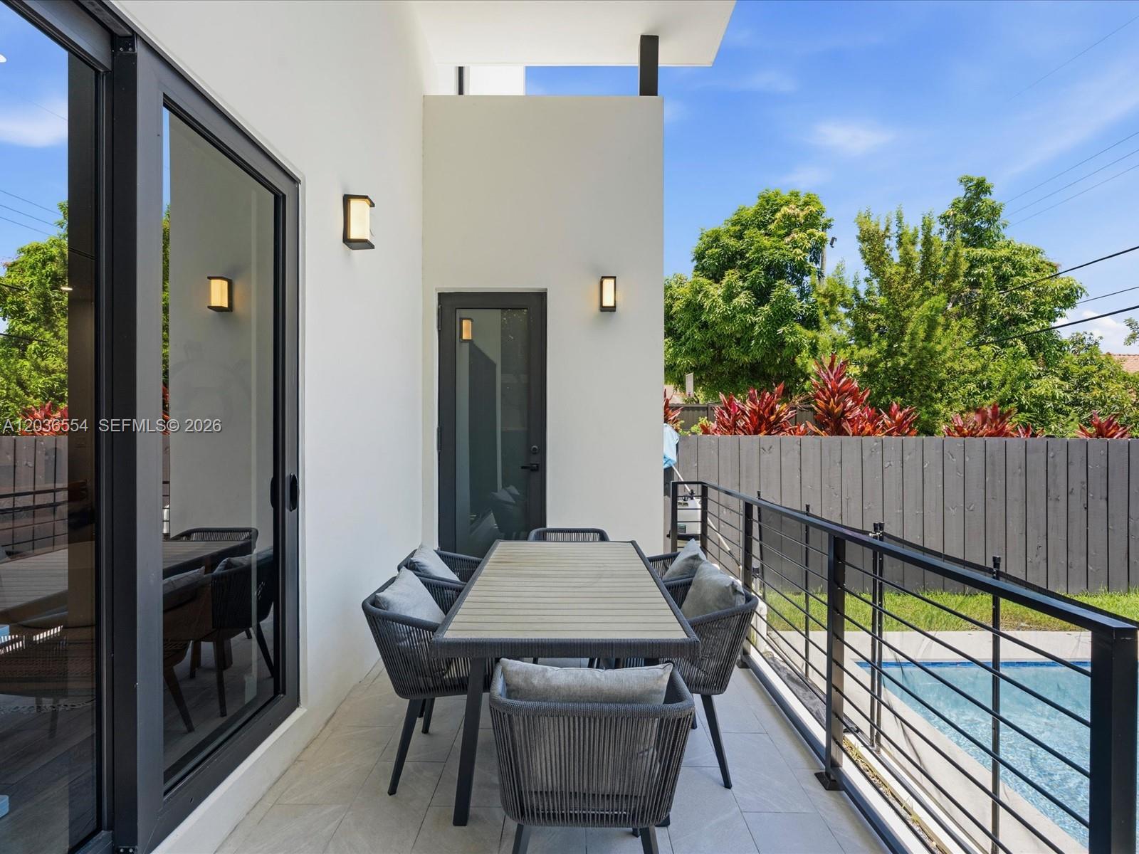 A modern outdoor patio features a dining set, white walls, and a pool view — 3266 SW 25th Ter # 3266, Miami FL 33133, MIAMI, FL